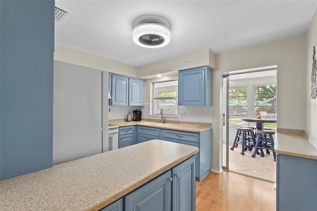 409 Archibald Ave, Sarasota, FL 34243 - kitchen with blue cabinets, light countertops, plenty of natural light, and light wood-style floors