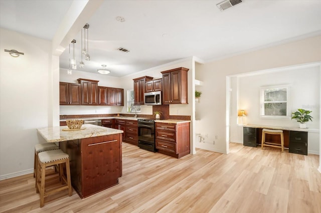 520 27th St W, Bradenton, FL 34205 - kitchen featuring appliances with stainless steel finishes, a kitchen breakfast bar, light wood-type flooring, and light stone countertops