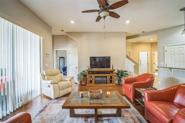 3041 Stonegate Falls Dr, Land O Lakes, FL 34638 - living area with wood finished floors, a ceiling fan, recessed lighting, a textured ceiling, and a glass covered fireplace