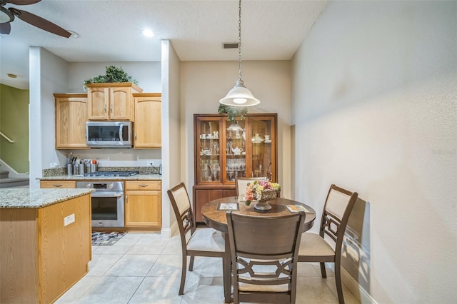 3041 Stonegate Falls Dr, Land O Lakes, FL 34638 - kitchen with appliances with stainless steel finishes, ceiling fan, light stone counters, hanging light fixtures, and a textured ceiling