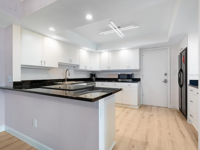 2295 Gulf Of Mexico Dr Unit 64S, Longboat Key, FL 34228 - kitchen with stainless steel microwave, light wood-style floors, a peninsula, dark countertops, and recessed lighting
