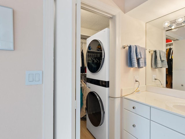 2295 Gulf Of Mexico Dr Unit 64S, Longboat Key, FL 34228 - laundry area featuring stacked washer and clothes dryer, light wood-style floors, and a textured ceiling