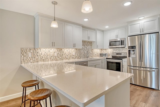 4325 Gulf Of Mexico Dr Unit 204, Longboat Key, FL 34228 - kitchen featuring appliances with stainless steel finishes, a peninsula, a breakfast bar area, white cabinets, and light wood-style flooring