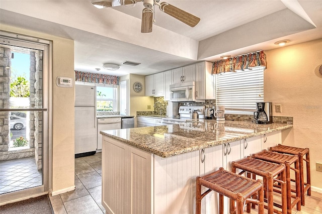 4325 Gulf Of Mexico Dr Unit 204, Longboat Key, FL 34228 - kitchen featuring white appliances, a peninsula, light stone counters, ceiling fan, and a textured wall