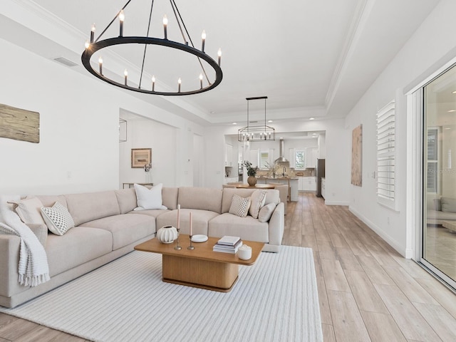 10120 Carnoustie Pl, Bradenton, FL 34211 - living area with a raised ceiling, a chandelier, light wood-style floors, and crown molding