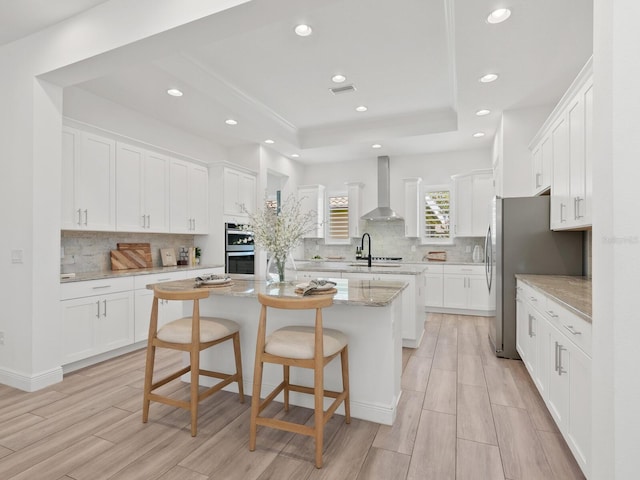 10120 Carnoustie Pl, Bradenton, FL 34211 - kitchen with wall chimney range hood, a raised ceiling, a center island, recessed lighting, and stainless steel appliances
