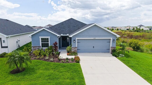 6435 165th Dr E, Parrish, FL 34219 - ranch-style house with stone siding, stucco siding, an attached garage, a front lawn, and concrete driveway