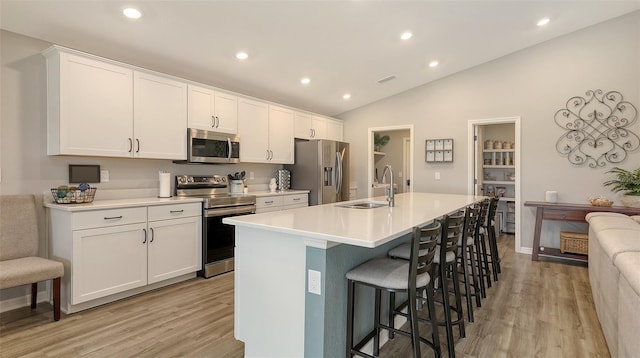 6435 165th Dr E, Parrish, FL 34219 - kitchen featuring appliances with stainless steel finishes, light wood-style flooring, a kitchen breakfast bar, a center island with sink, and recessed lighting