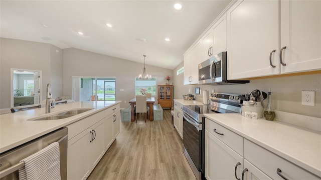 6435 165th Dr E, Parrish, FL 34219 - kitchen with appliances with stainless steel finishes, light wood-style floors, vaulted ceiling, light countertops, and white cabinetry