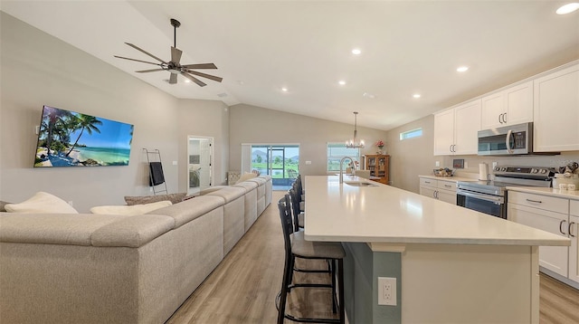 6435 165th Dr E, Parrish, FL 34219 - kitchen with appliances with stainless steel finishes, open floor plan, lofted ceiling, light wood finished floors, and an island with sink