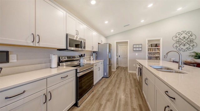 6435 165th Dr E, Parrish, FL 34219 - kitchen with stainless steel appliances, white cabinetry, light countertops, vaulted ceiling, and light wood-style floors