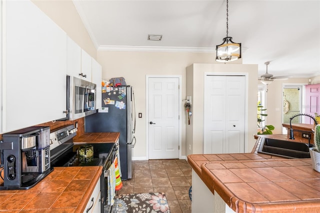 6178 Coliseum Blvd, Port Charlotte, FL 33981 - kitchen featuring stainless steel appliances, tile counters, crown molding, white cabinetry, and pendant lighting
