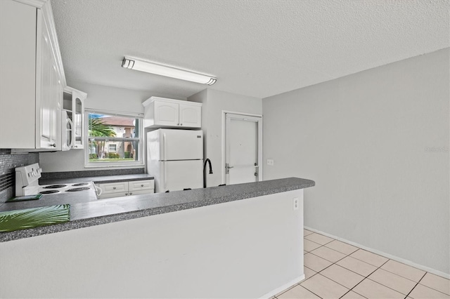 25100 Sandhill Blvd Unit 104G, Punta Gorda, FL 33983 - kitchen with white appliances, dark countertops, a peninsula, white cabinetry, and light tile patterned floors