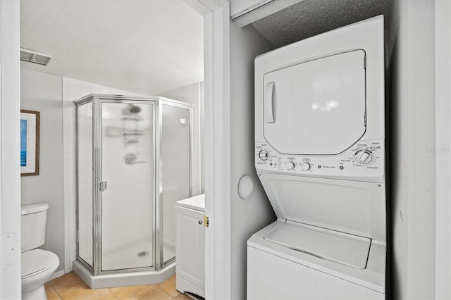 25100 Sandhill Blvd Unit 104G, Punta Gorda, FL 33983 - bathroom with stacked washer / dryer, a shower stall, tile patterned flooring, and a textured ceiling
