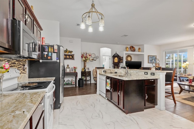 25324 Alicante Dr, Punta Gorda, FL 33955 - kitchen with white appliances, arched walkways, a chandelier, backsplash, and a center island with sink