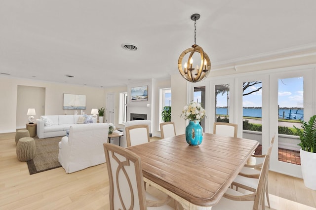2401 Riverview Blvd, Bradenton, FL 34205 - dining space with a chandelier, light wood finished floors, ornamental molding, and a fireplace