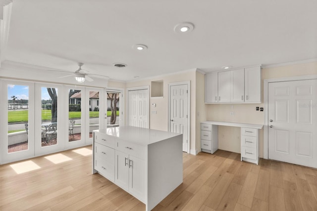 2401 Riverview Blvd, Bradenton, FL 34205 - kitchen with ornamental molding, recessed lighting, light wood-type flooring, white cabinetry, and light countertops