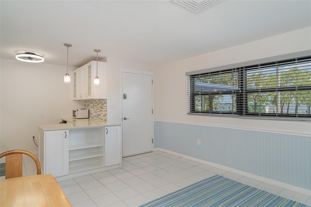 1400 1st Ave W Unit 103, Bradenton, FL 34205 - kitchen with open shelves, a wainscoted wall, white cabinetry, light countertops, and glass insert cabinets