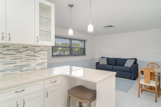 1400 1st Ave W Unit 103, Bradenton, FL 34205 - kitchen featuring light tile patterned floors, a wainscoted wall, white cabinets, backsplash, and pendant lighting