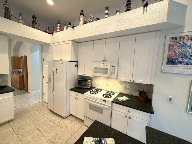 8616 15th Ave NW, Bradenton, FL 34209 - kitchen featuring white appliances, backsplash, light tile patterned flooring, and dark countertops