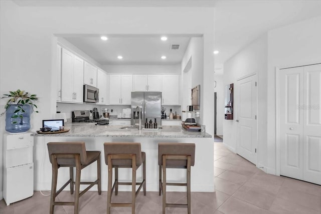 15131 Sunny Day Dr, Bradenton, FL 34211 - kitchen featuring stainless steel appliances, a peninsula, white cabinetry, a breakfast bar area, and recessed lighting