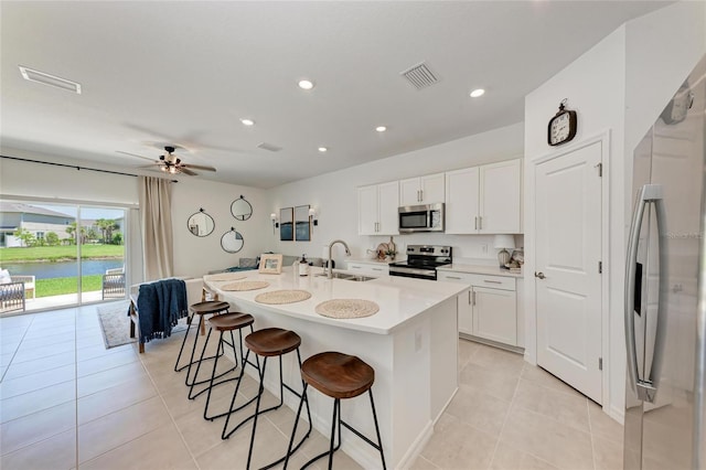 5711 Archipelago St, Nokomis, FL 34275 - kitchen featuring stainless steel appliances, a kitchen breakfast bar, light tile patterned flooring, a kitchen island with sink, and white cabinetry