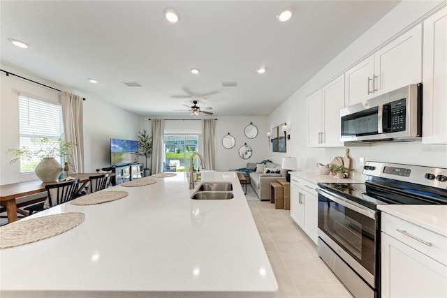 5711 Archipelago St, Nokomis, FL 34275 - kitchen featuring appliances with stainless steel finishes, open floor plan, light tile patterned floors, a kitchen island with sink, and light countertops