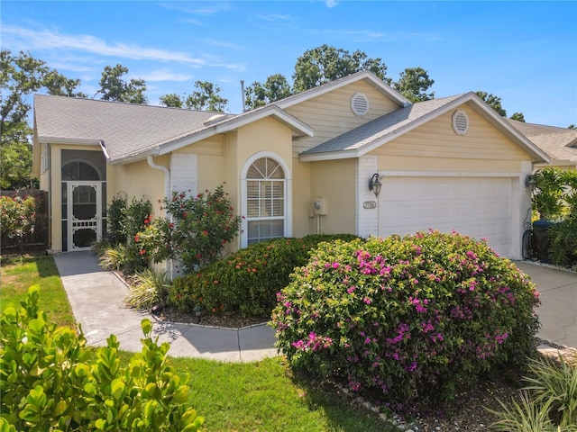 7716 Geneva Ln, Sarasota, FL 34243 - view of front of property with an attached garage, stucco siding, and roof with shingles