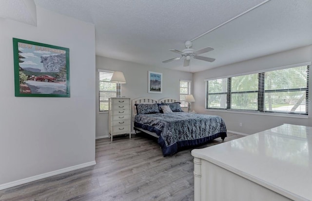 7110 Fairway Bend Ln Unit 181, Sarasota, FL 34243 - bedroom with multiple windows, light wood finished floors, a textured ceiling, and a ceiling fan