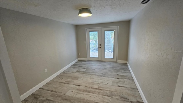 1240 Solitude Ln, Sarasota, FL 34242 - doorway with french doors, a textured wall, light wood finished floors, and a textured ceiling