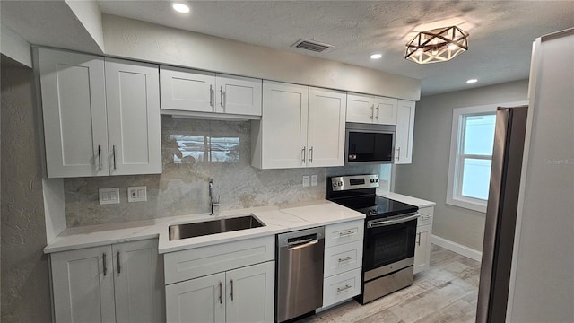 1240 Solitude Ln, Sarasota, FL 34242 - kitchen featuring appliances with stainless steel finishes, decorative backsplash, recessed lighting, white cabinetry, and light stone counters
