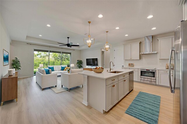 918 Fernleaf Run, Bradenton, FL 34212 - kitchen featuring wall chimney range hood, appliances with stainless steel finishes, open floor plan, recessed lighting, and light wood-type flooring