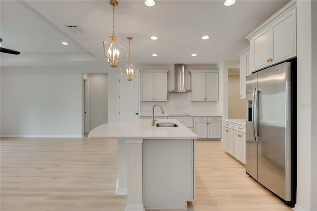 918 Fernleaf Run, Bradenton, FL 34212 - kitchen with stainless steel fridge, wall chimney range hood, light wood-style flooring, light countertops, and recessed lighting