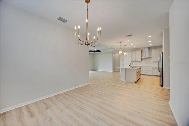 918 Fernleaf Run, Bradenton, FL 34212 - kitchen featuring wall chimney exhaust hood, a chandelier, open floor plan, light wood-type flooring, and freestanding refrigerator