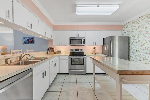 3810 75th St W Unit 128, Bradenton, FL 34209 - kitchen featuring appliances with stainless steel finishes, light countertops, wallpapered walls, crown molding, and white cabinetry