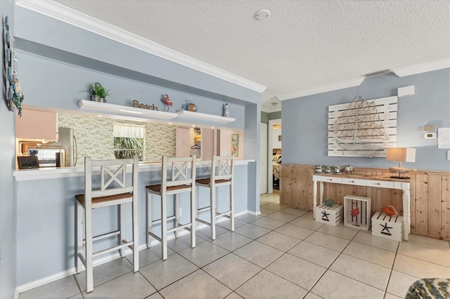3810 75th St W Unit 128, Bradenton, FL 34209 - kitchen featuring crown molding, a textured ceiling, freestanding refrigerator, tile patterned flooring, and a kitchen breakfast bar