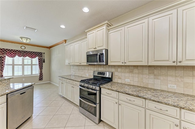 6516 Palm Leaf Ct, Sarasota, FL 34243 - kitchen with appliances with stainless steel finishes, light tile patterned floors, decorative backsplash, crown molding, and light stone counters
