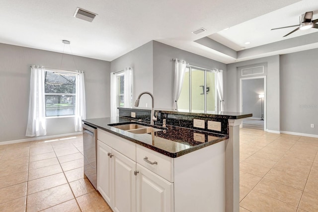 5005 Torrey Pines Run, Bradenton, FL 34211 - kitchen with light tile patterned floors, stainless steel dishwasher, dark stone countertops, and an island with sink
