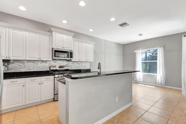 5005 Torrey Pines Run, Bradenton, FL 34211 - kitchen featuring appliances with stainless steel finishes, light tile patterned flooring, white cabinetry, decorative backsplash, and a kitchen island with sink