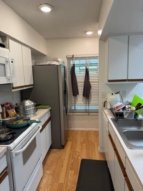 3404 56th Dr E, Bradenton, FL 34203 - kitchen featuring white appliances, light wood-type flooring, white cabinetry, and light countertops