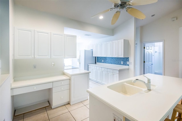 7137 Cedar Hollow Cir, Bradenton, FL 34203 - kitchen featuring light tile patterned floors, white cabinets, built in desk, and backsplash