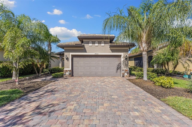 19023 Mangieri St, Venice, FL 34293 - mediterranean / spanish-style house featuring stucco siding, decorative driveway, an attached garage, a tile roof, and stone siding