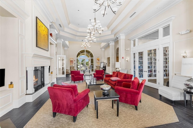 19023 Mangieri St, Venice, FL 34293 - living area with a chandelier, dark wood-style flooring, crown molding, a lit fireplace, and french doors