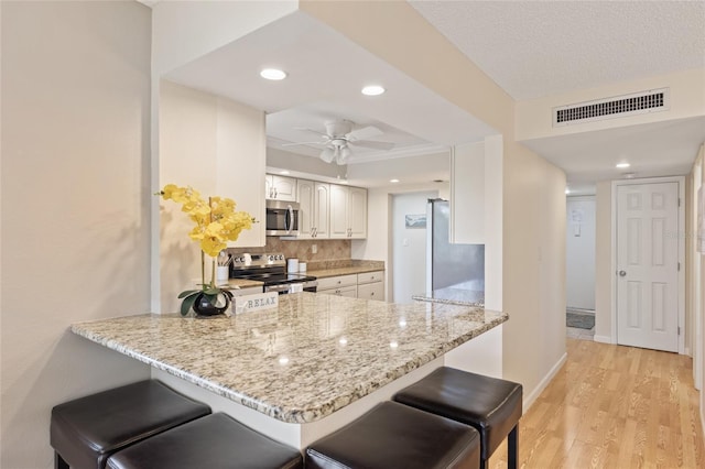 6265 Midnight Pass Rd Unit 205, Sarasota, FL 34242 - kitchen featuring stainless steel appliances, a peninsula, light wood-style floors, a ceiling fan, and decorative backsplash