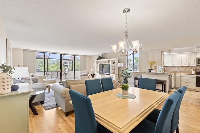 6265 Midnight Pass Rd Unit 205, Sarasota, FL 34242 - dining space featuring a chandelier, light wood-type flooring, and a textured ceiling