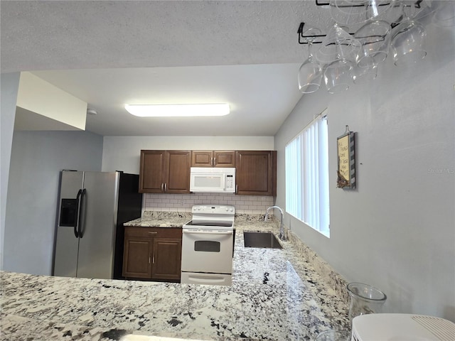4001 Beneva Rd Unit 319, Sarasota, FL 34233 - kitchen with white appliances, decorative backsplash, light stone counters, and dark brown cabinets