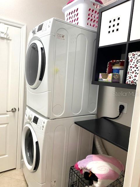 7750 Ridgelake Cir, Bradenton, FL 34203 - laundry area with stacked washer / dryer and light tile patterned floors