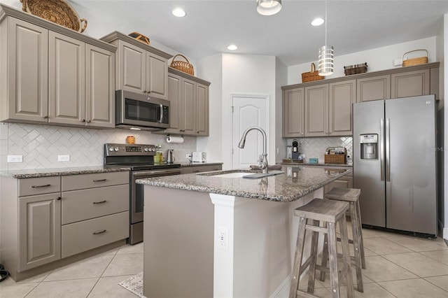 7750 Ridgelake Cir, Bradenton, FL 34203 - kitchen with stainless steel appliances, gray cabinetry, light tile patterned floors, backsplash, and a kitchen island with sink