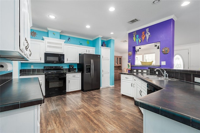 6710 36th Ave E Unit 114, Palmetto, FL 34221 - kitchen featuring black appliances, dark countertops, ornamental molding, white cabinets, and dark wood-type flooring