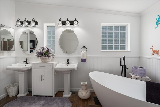 6710 36th Ave E Unit 114, Palmetto, FL 34221 - bathroom featuring a wainscoted wall, wood finished floors, a soaking tub, crown molding, and two sinks